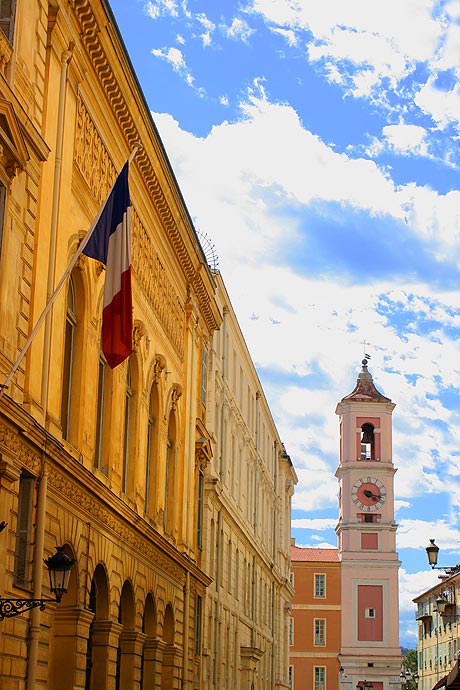 Immeuble avec un drapeau et tour de l'horloge d'une eglise a Nice photo